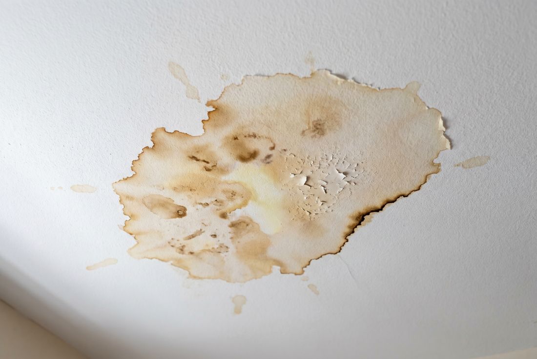 Water-damaged ceiling with brown stain, peeling paint, and bubbling drywall &mdash; Aurora water damaged ceiling repair